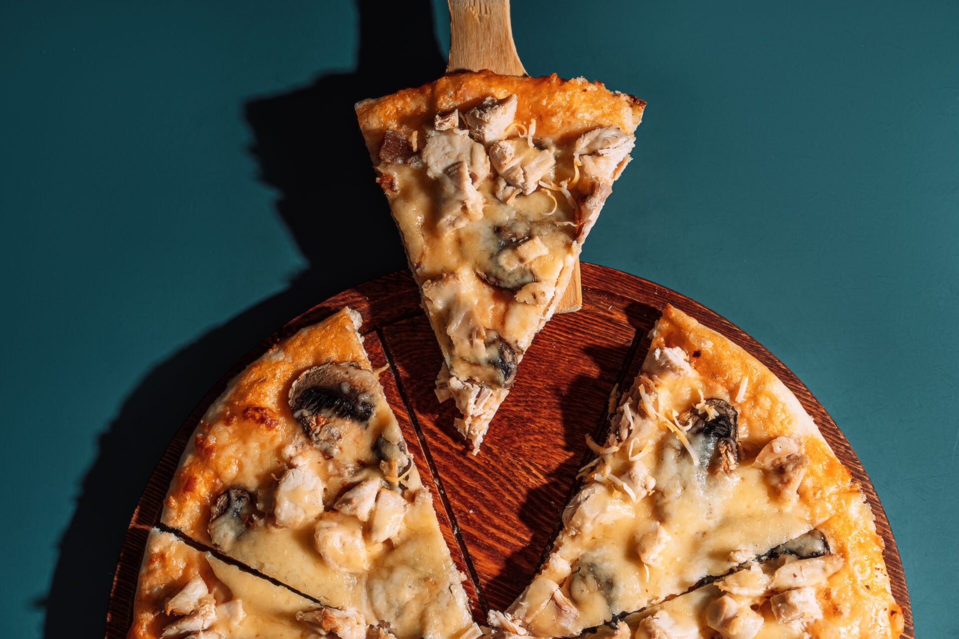 Mushroom pizza cut into equal parts on wooden tray